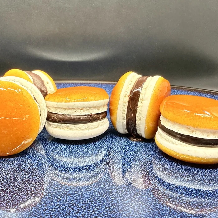 Narancsszínű és krémszínű macaronok egymás mellett